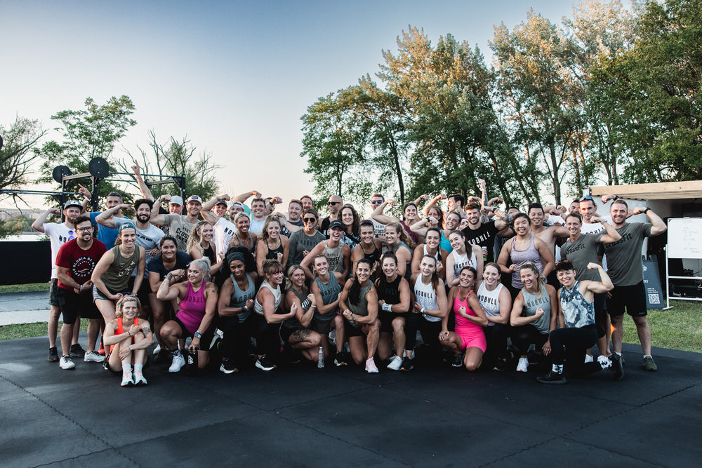 A group of crossfit athletes posing for a picture after their workout wearing athletic clothes and training shoes