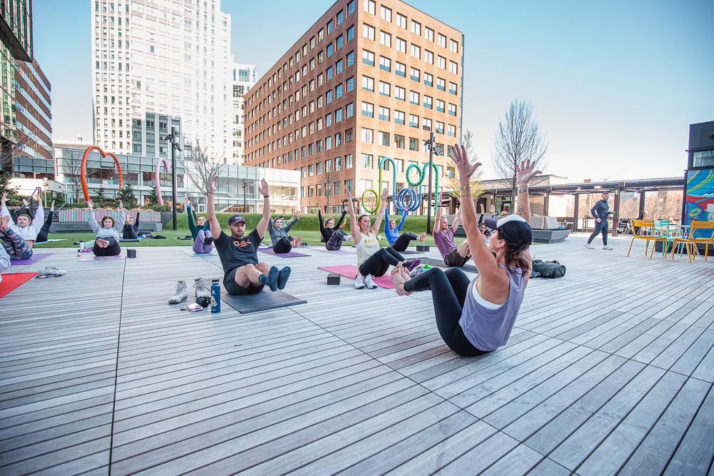 Outdoor workout class of athletic individuals wearing casual athletic clothes doing Yoga
