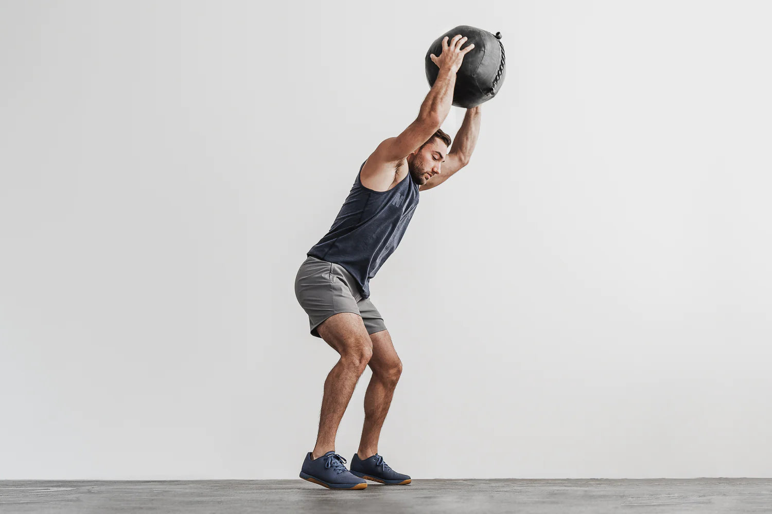 Athletic man is working out in athletic clothing and cross training shoes while throwing a medicine ball