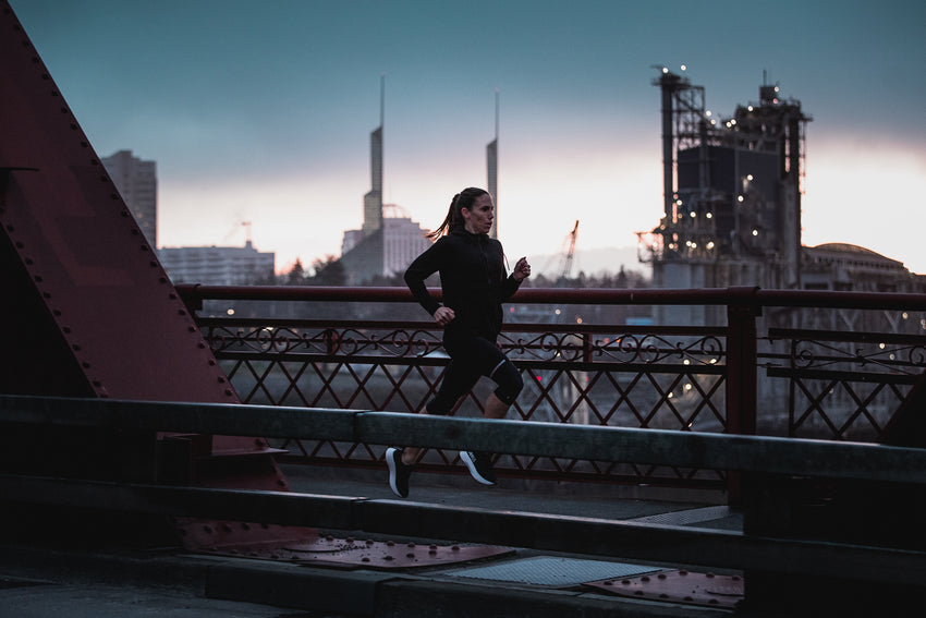 female athlete running outside at dusk