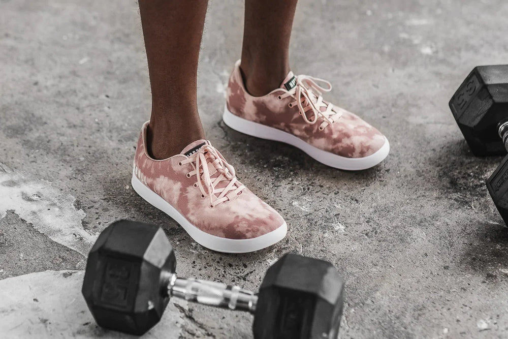 An athlete wearing Blush colored mesh running shoes prepares for a workout with dumbells