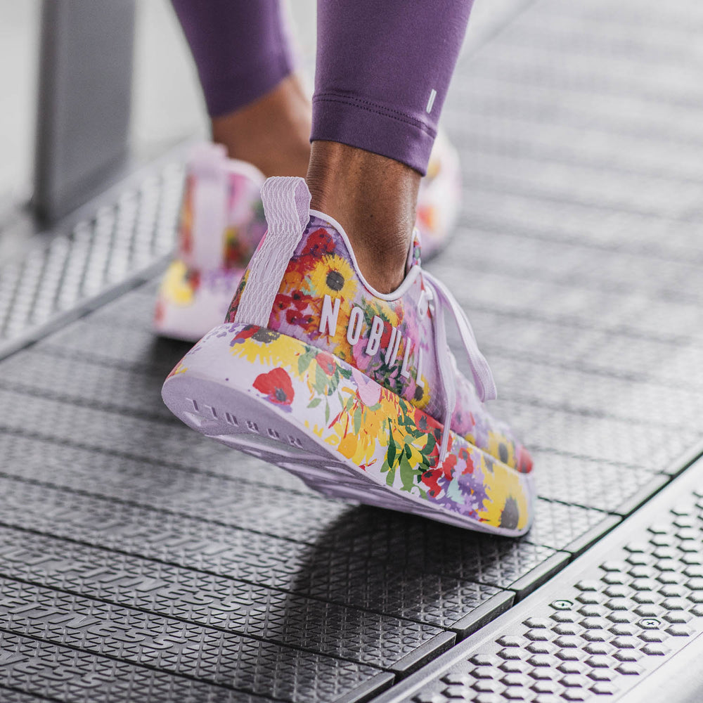 An athletic woman wearing purple workout apparel trains while wearing transparent purple floral print ripstop sneakers